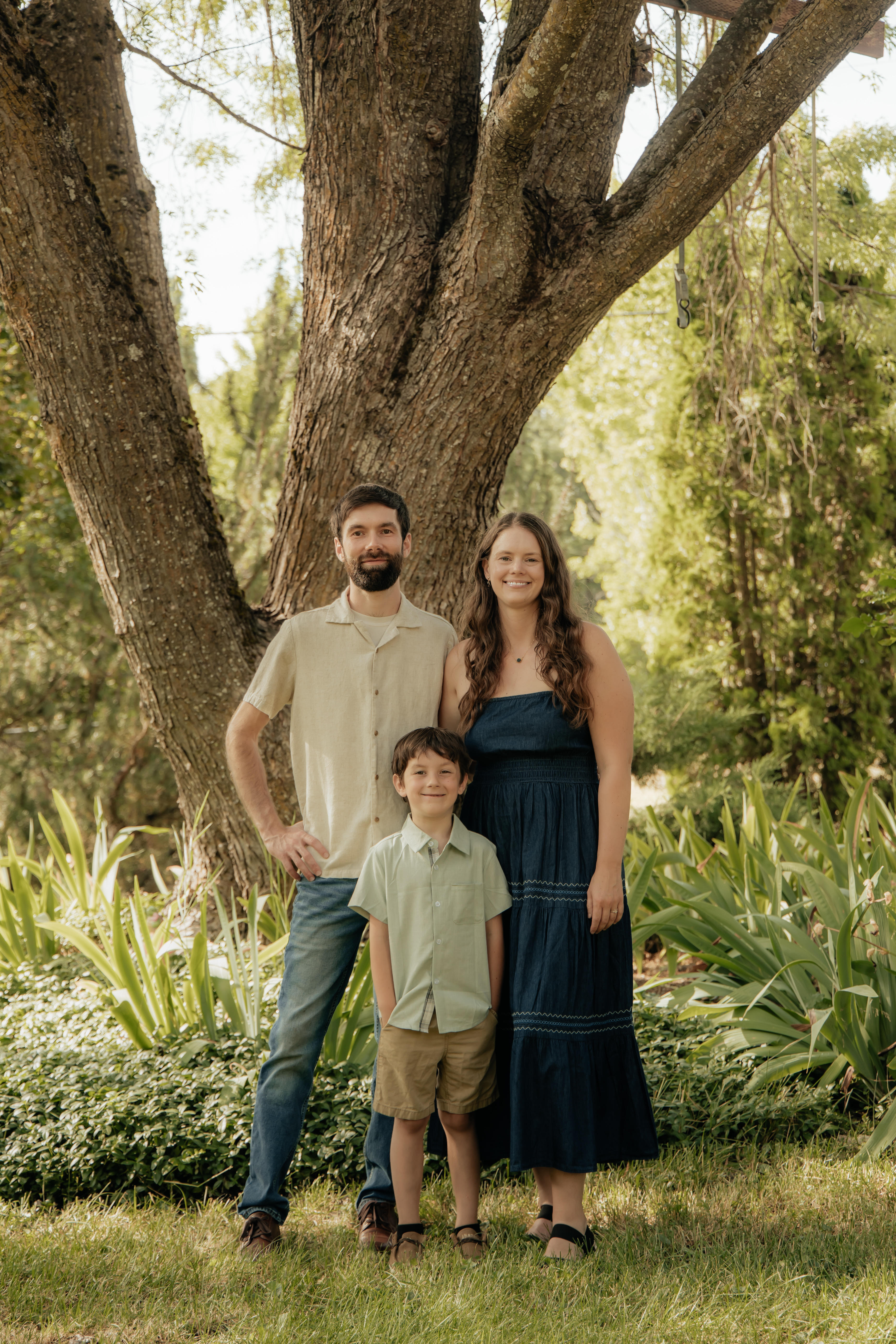 A family of three standing together before a large tree, reflecting the small-business owners and communities Acumen Bookkeeping supports.